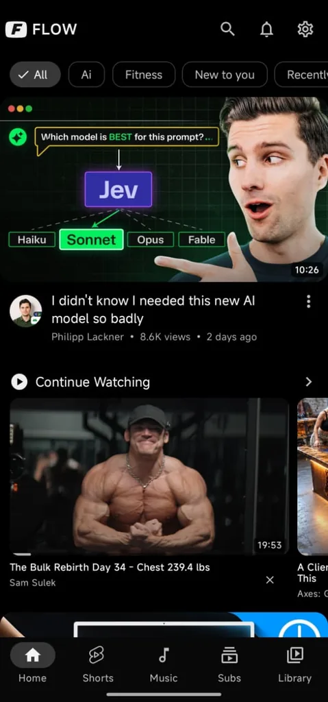Home di Flow: in alto le etichette degli interessi «All», «Ai», «Fitness», «New to you», sotto un video consigliato con la miniatura grande e lo scaffale «Continue Watching»; in basso la barra con Home, Shorts, Music, Subs e Library
